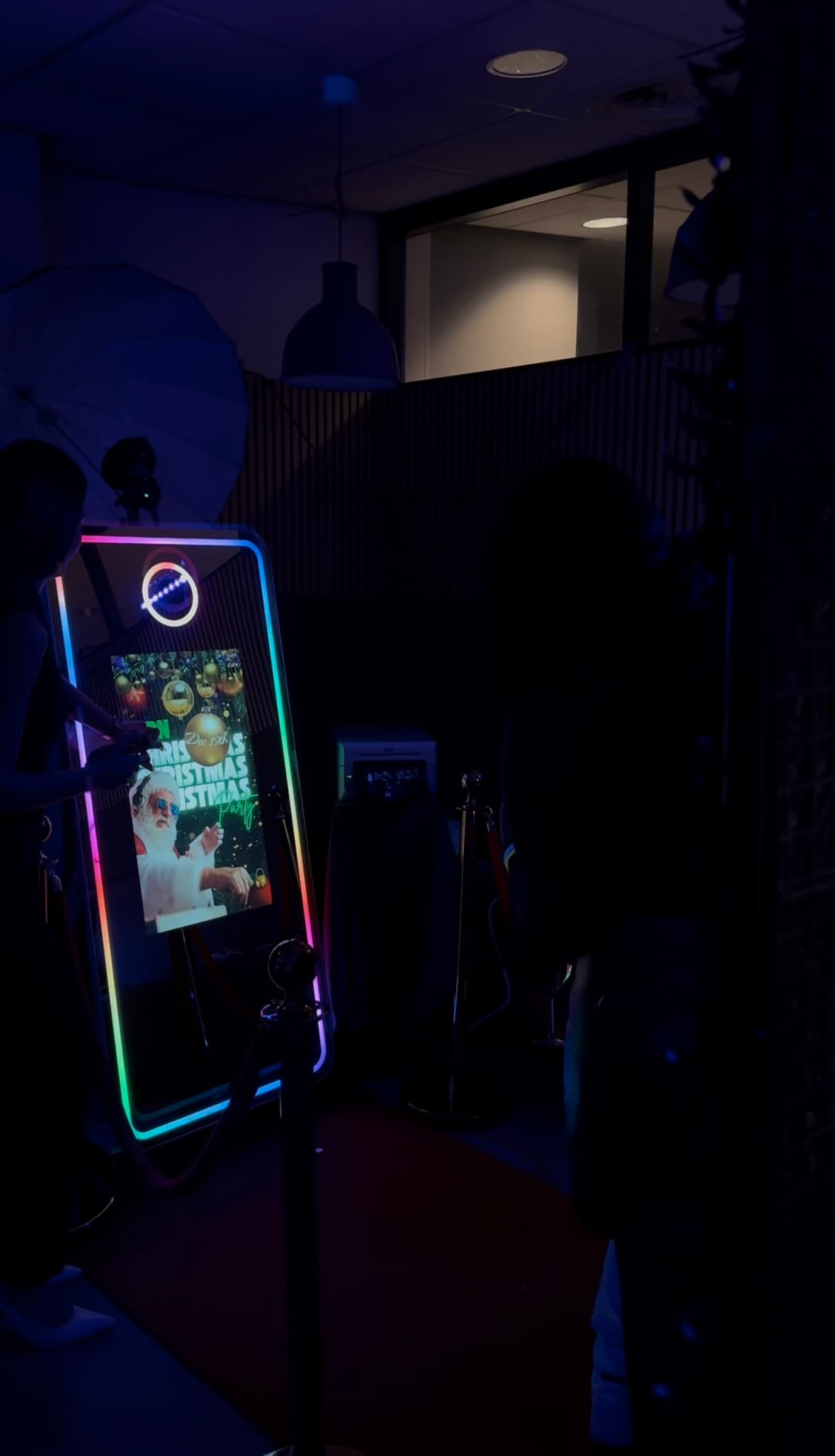 Gasten gebruiken de Norella Mirror Photobooth tijdens een donker verlicht event